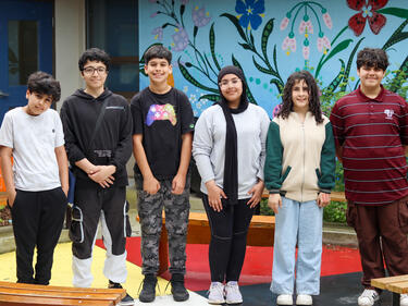 Six middle school students stand in a line, smiling at camera