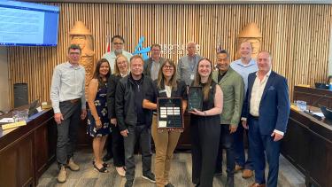 The board and the recipients of an awards stand in front of Abbotsford SD logo holding awards