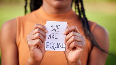 Anti-racism Image Out of focus women holds piece of paper that says "we are equal"