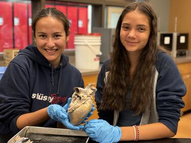 Two female students in science class holding an organ.