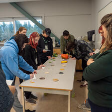 A small group of students around a table watching a demonstration
