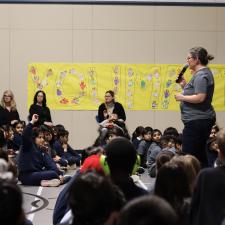 Principal stands in front of school and speaks to students, staff and parents for assembly.