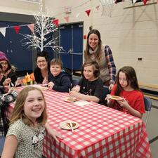 A small group of students and staff sitting at a table, enjoying a sweet treat