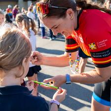 Tour de Valley rider signs pencil for young student.